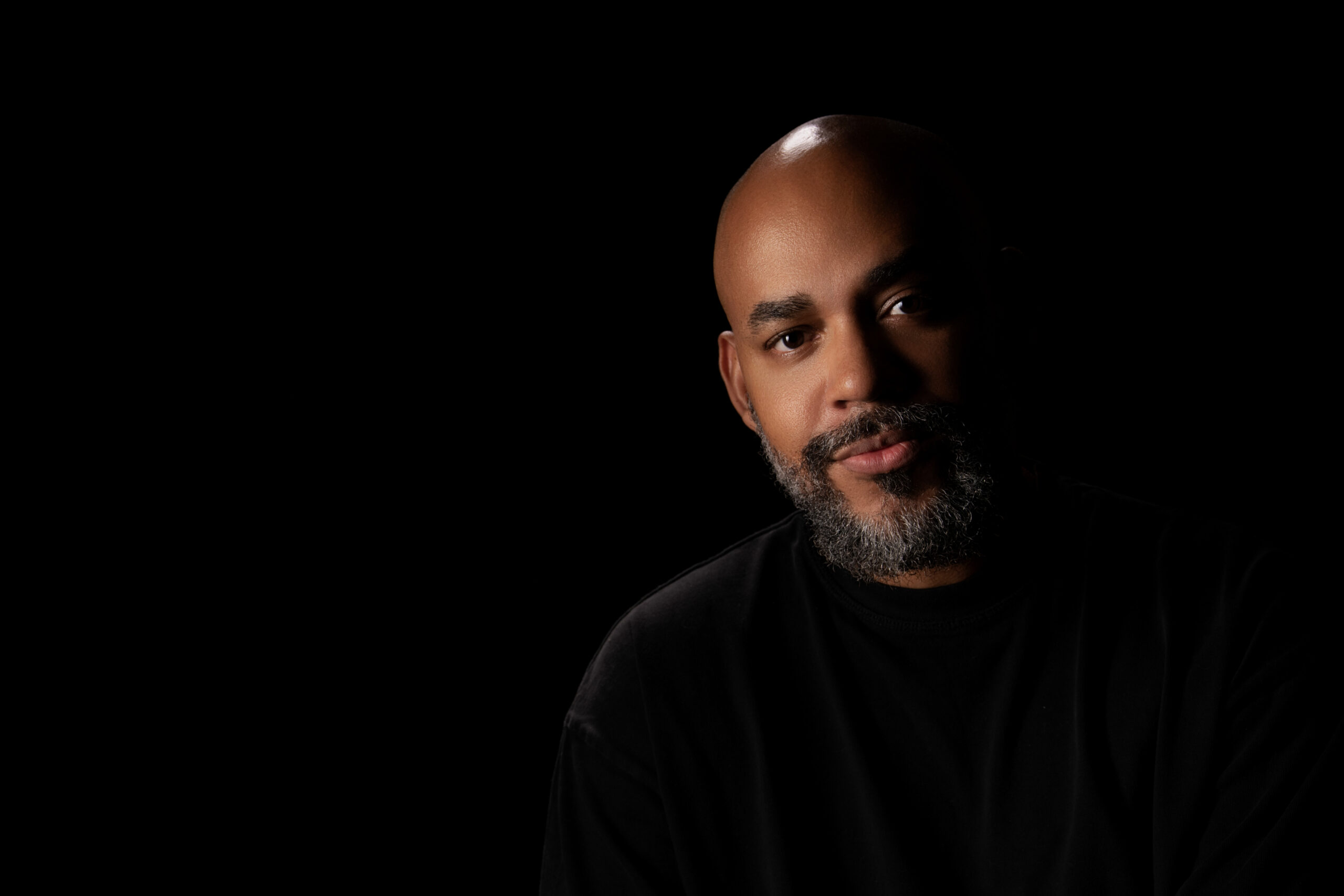 Retrato profesional de Mario Spencer, fotógrafo y videógrafo en Costa Rica, con iluminación de estudio sobre fondo negro.